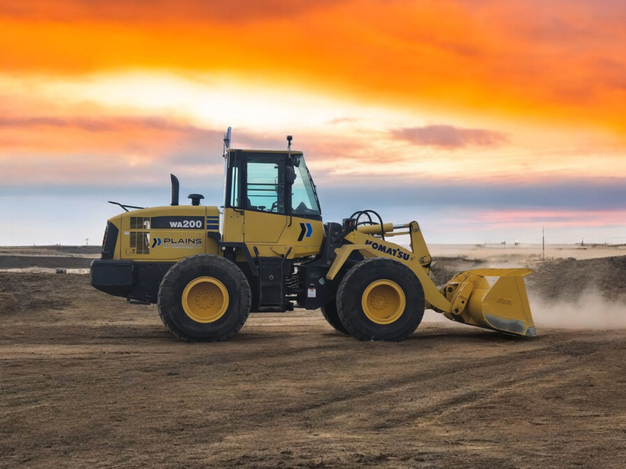 Komatsu WA200 loader from Plains Equipment Rentals operating in Western Canada, set against a vibrant sunset on an open construction site