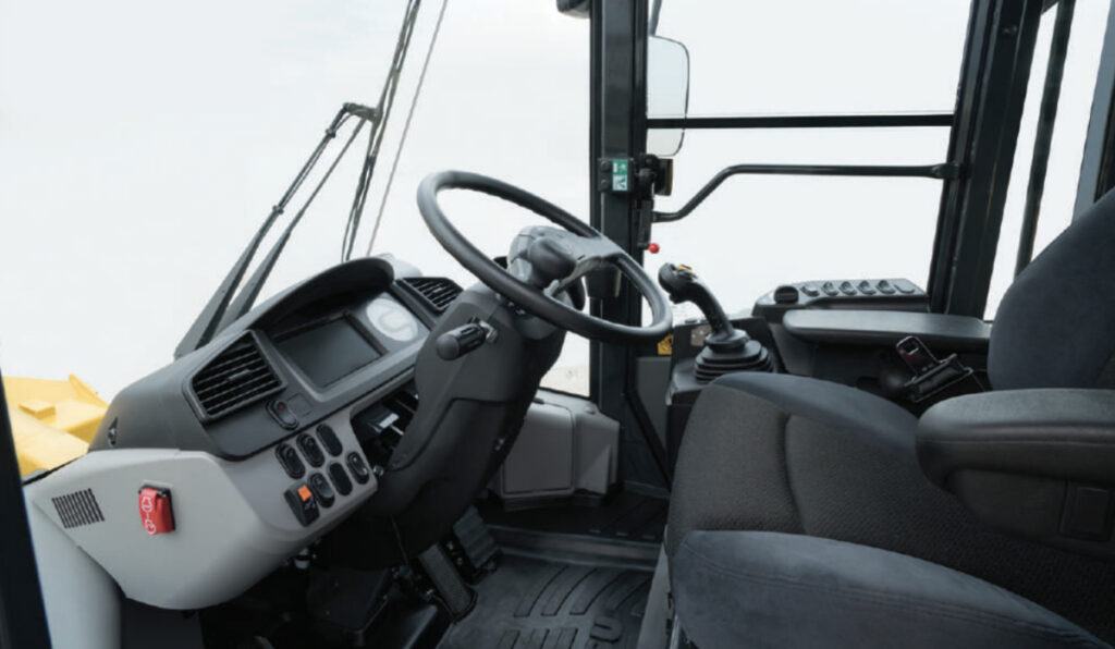 Operator cabin of a Komatsu WA320 wheel loader, showcasing ergonomic controls, a comfortable seat, and an advanced dashboard