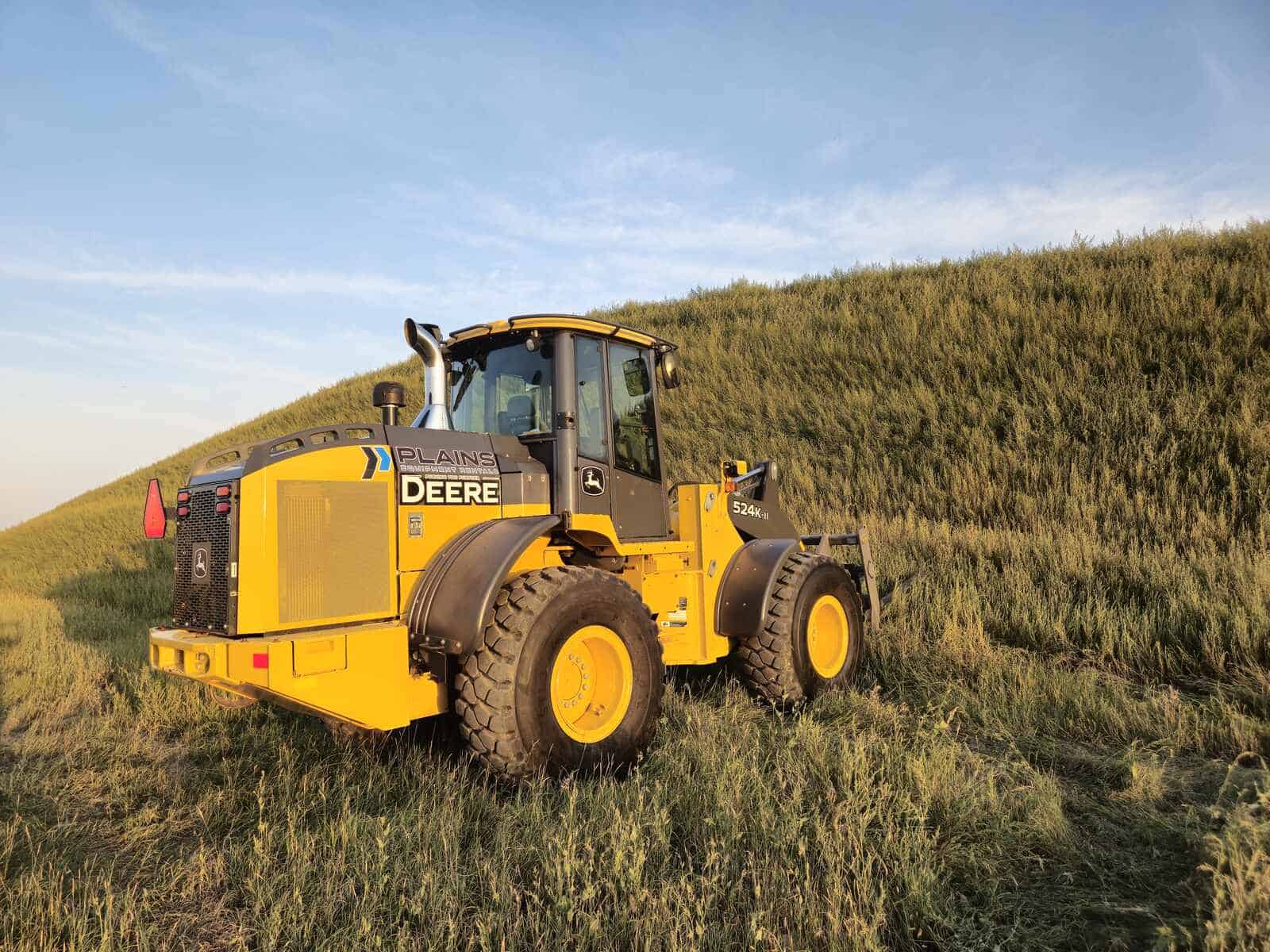 John Deere 524K-II wheel loader for sale, photographed in Western Canada field at sunset