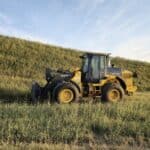 John Deere 524K-II wheel loader with pallet forks from Plains Equipment Rentals in Western Canada for sale, side view in field